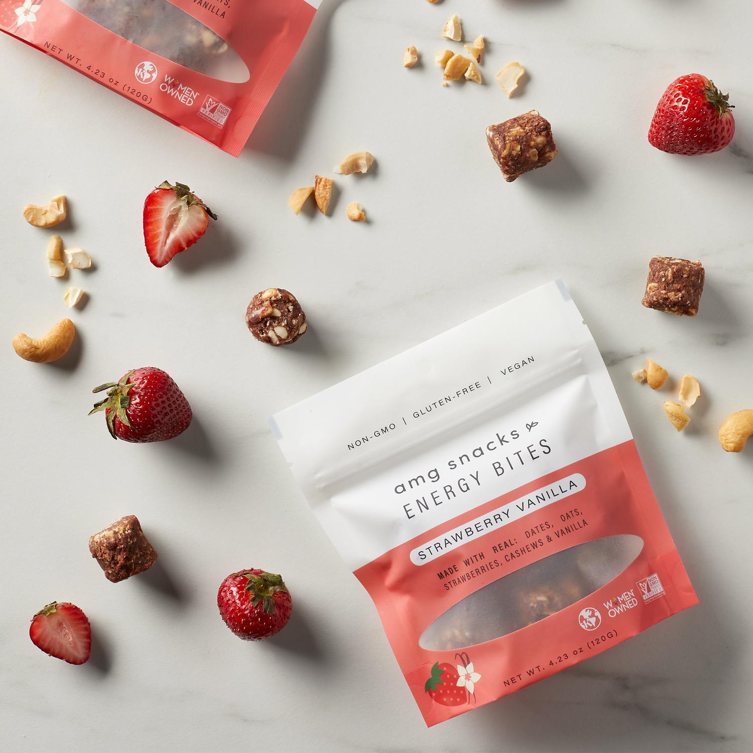Bag of AMG Snacks Strawberry Vanilla Energy Bites: strawberries and cashews scattered around.
